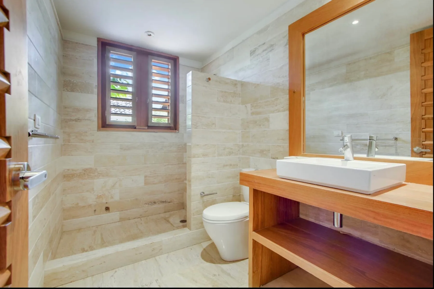 A tiled bathroom with a shower area, toilet, and sink.