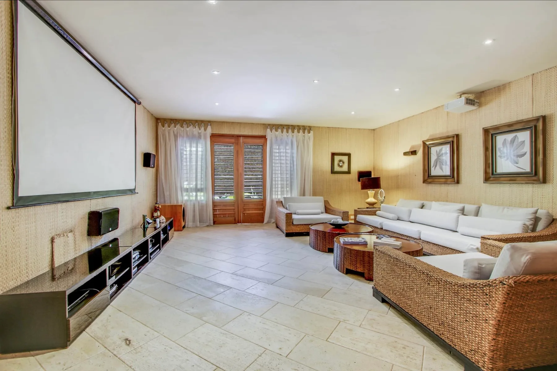 A living room with wicker seating, a large screen, and glass doors.