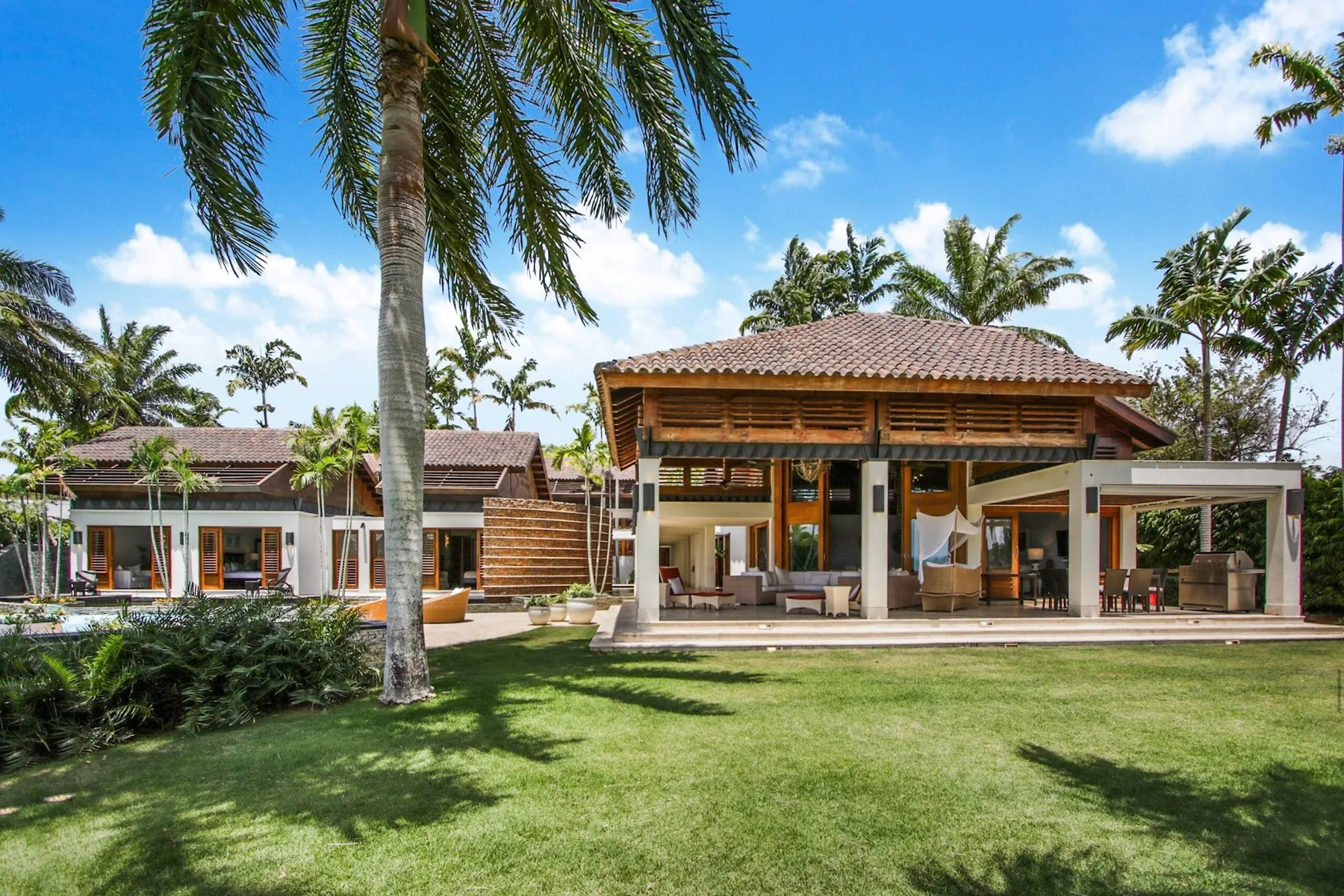 A tropical resort building opens onto a lawn beneath tall palm trees.