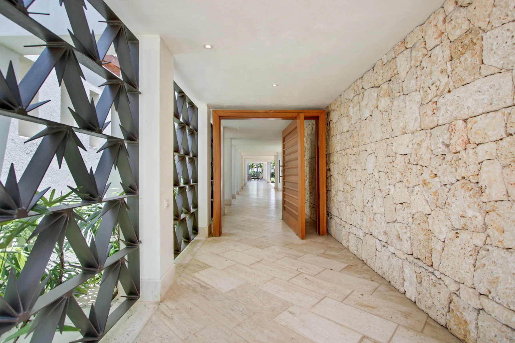 A bright hallway with a stone wall and an open wooden doorway.