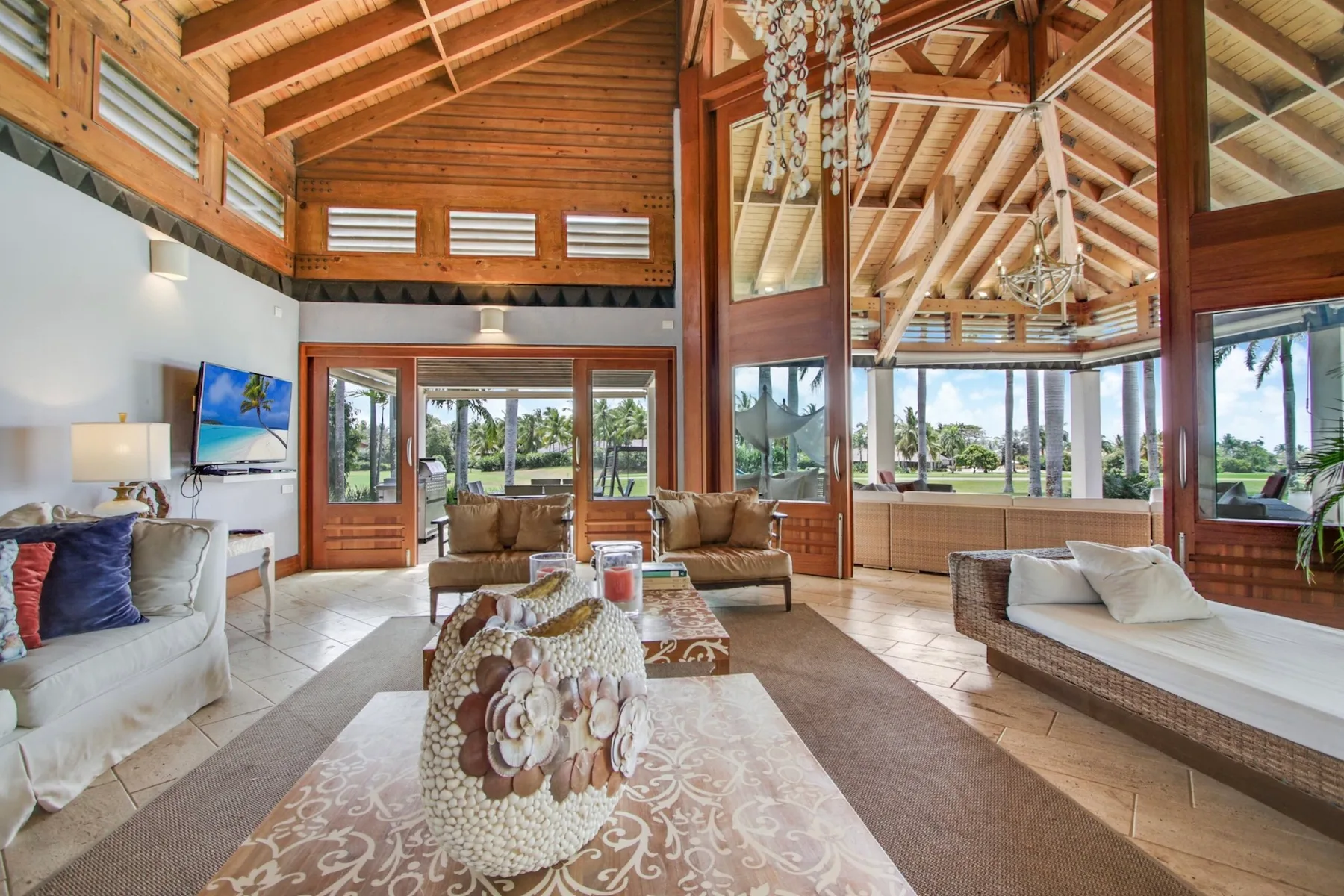 A spacious living room has large windows and an exposed wooden ceiling.