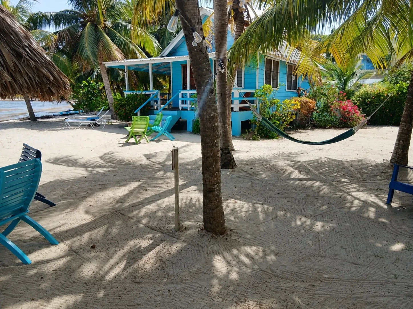 Cabaña azul frente a la playa con hamaca