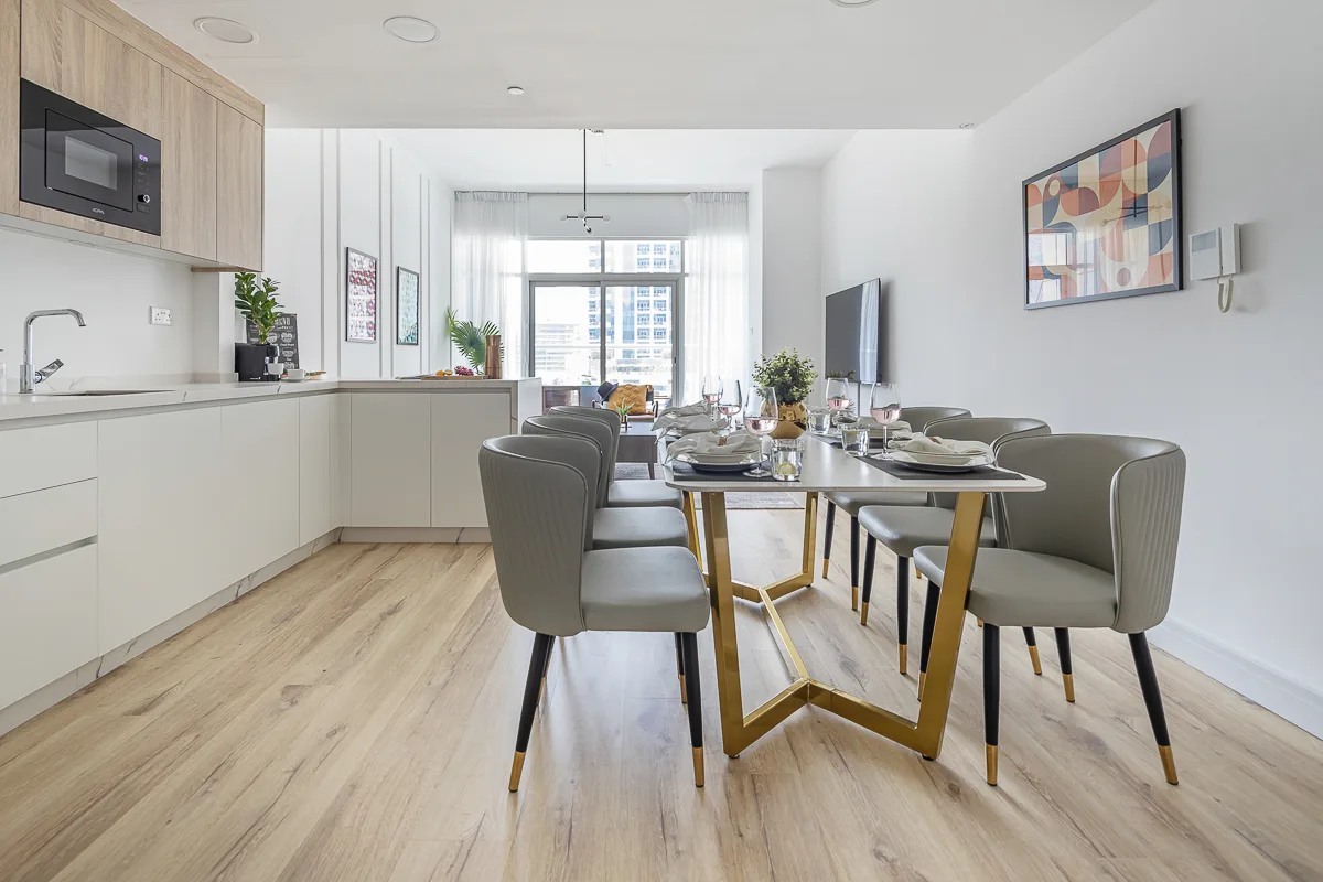 Cocina y comedor de concepto abierto, con la mesa puesta y ventanales.