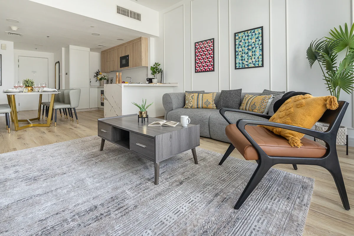 Una sala y comedor de concepto abierto con un sofá seccional gris y una mesa de centro.