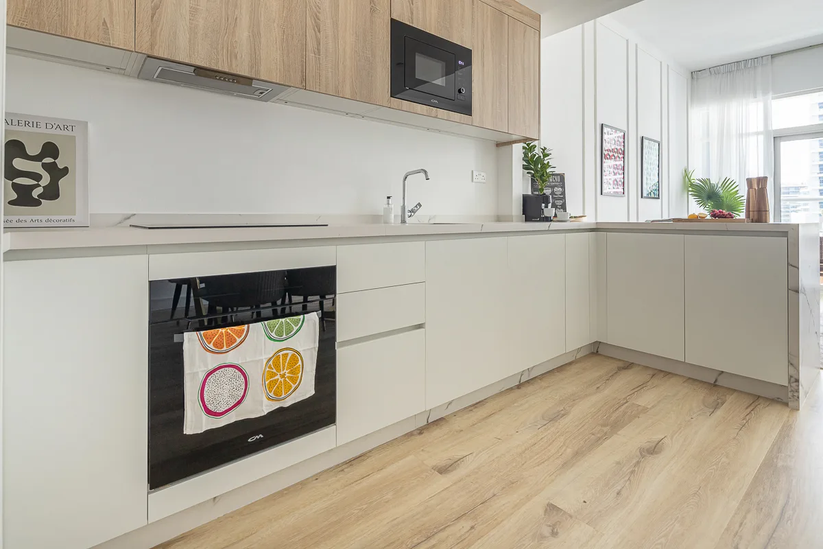 Una cocina moderna y luminosa con gabinetes claros y piso con acabado de madera.