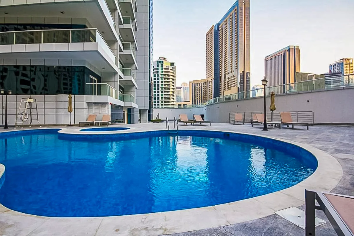 Una piscina azul está rodeada de asientos y edificios de gran altura.
