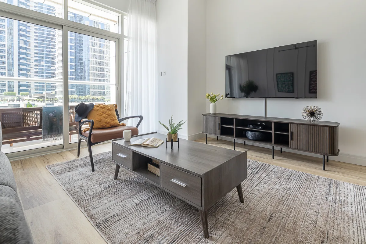 Una sala luminosa tiene un televisor grande sobre un mueble bajo.