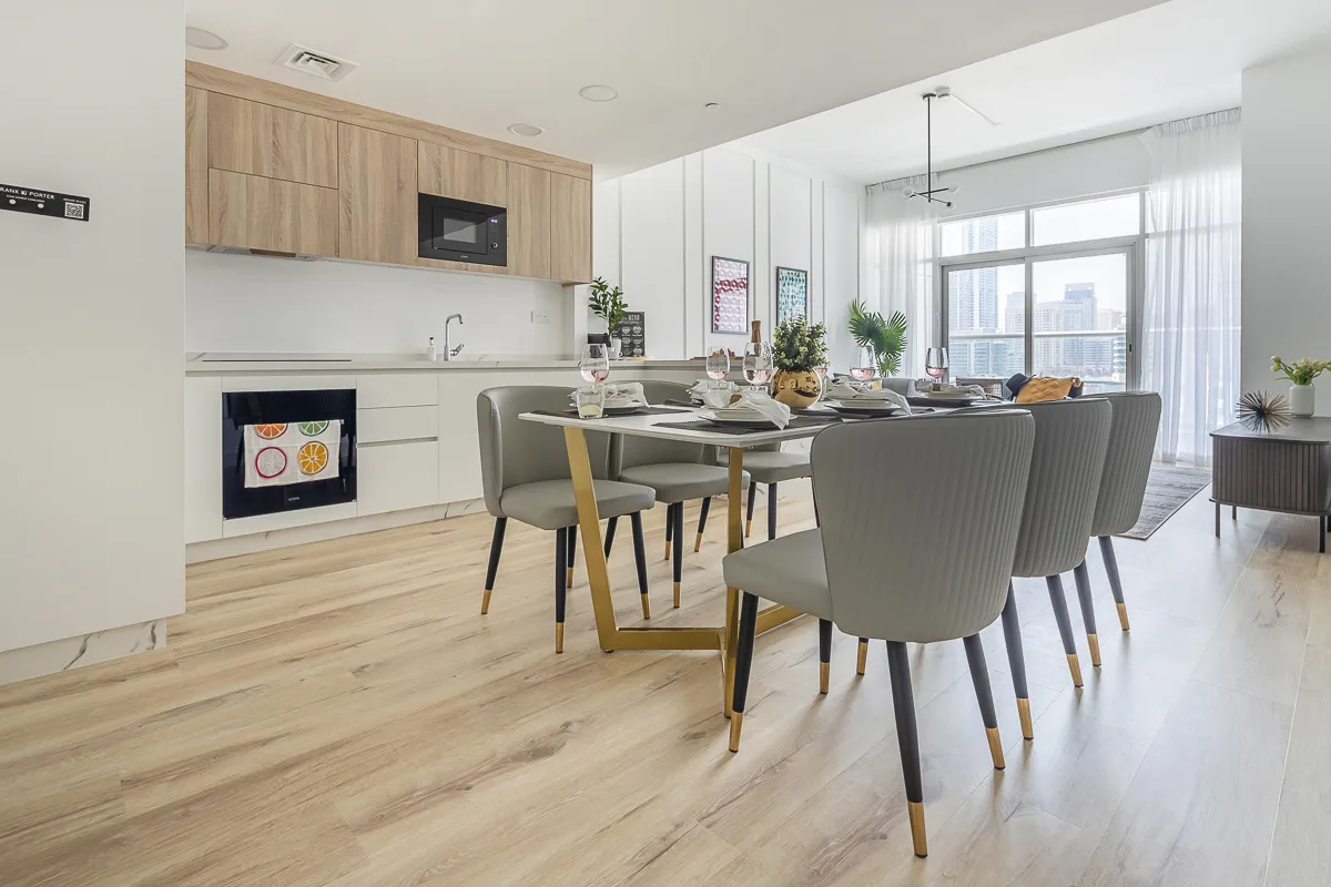 Comedor luminoso de planta abierta junto a una cocina moderna, con grandes ventanales.