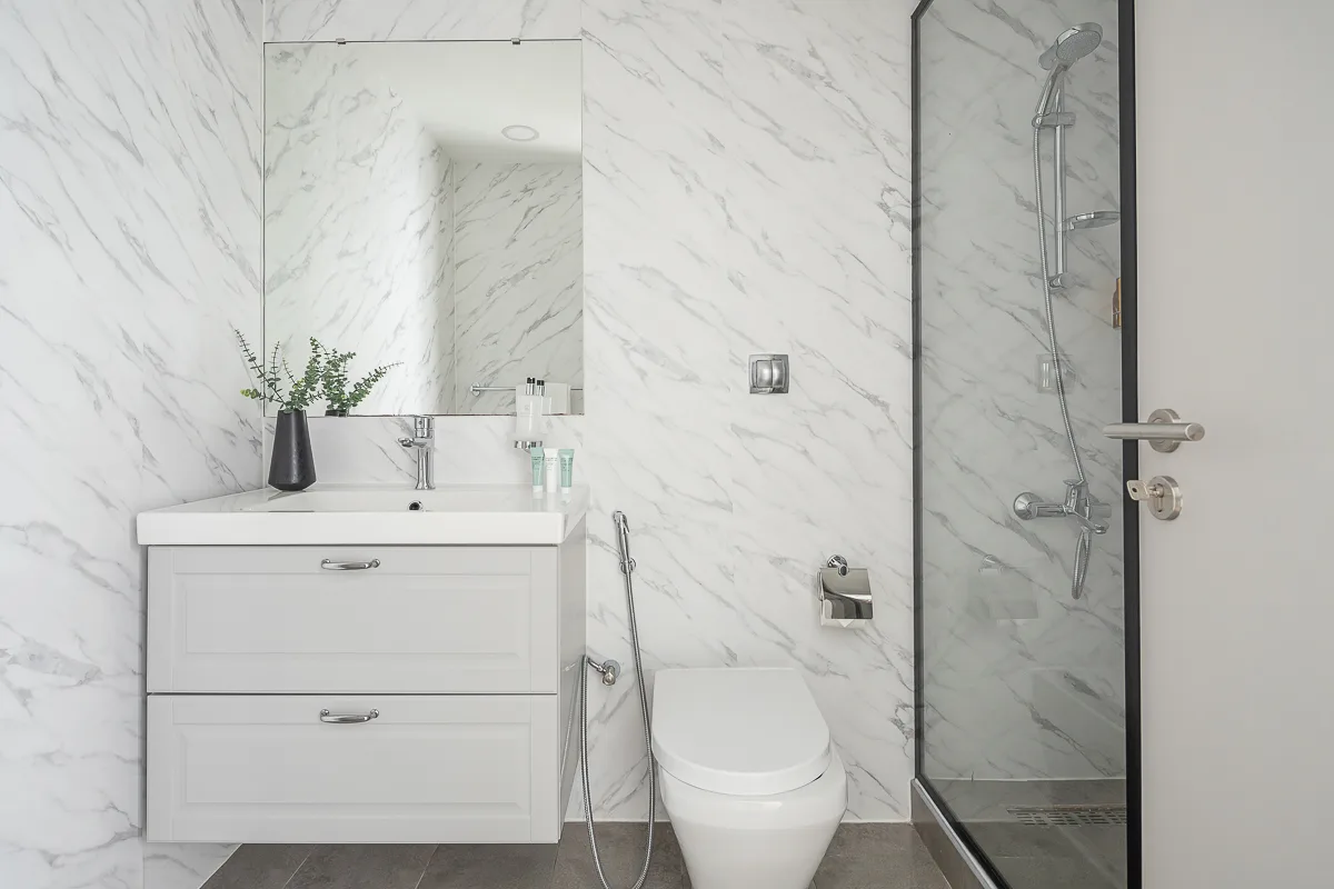 Un baño luminoso con lavabo, inodoro y ducha de cristal.