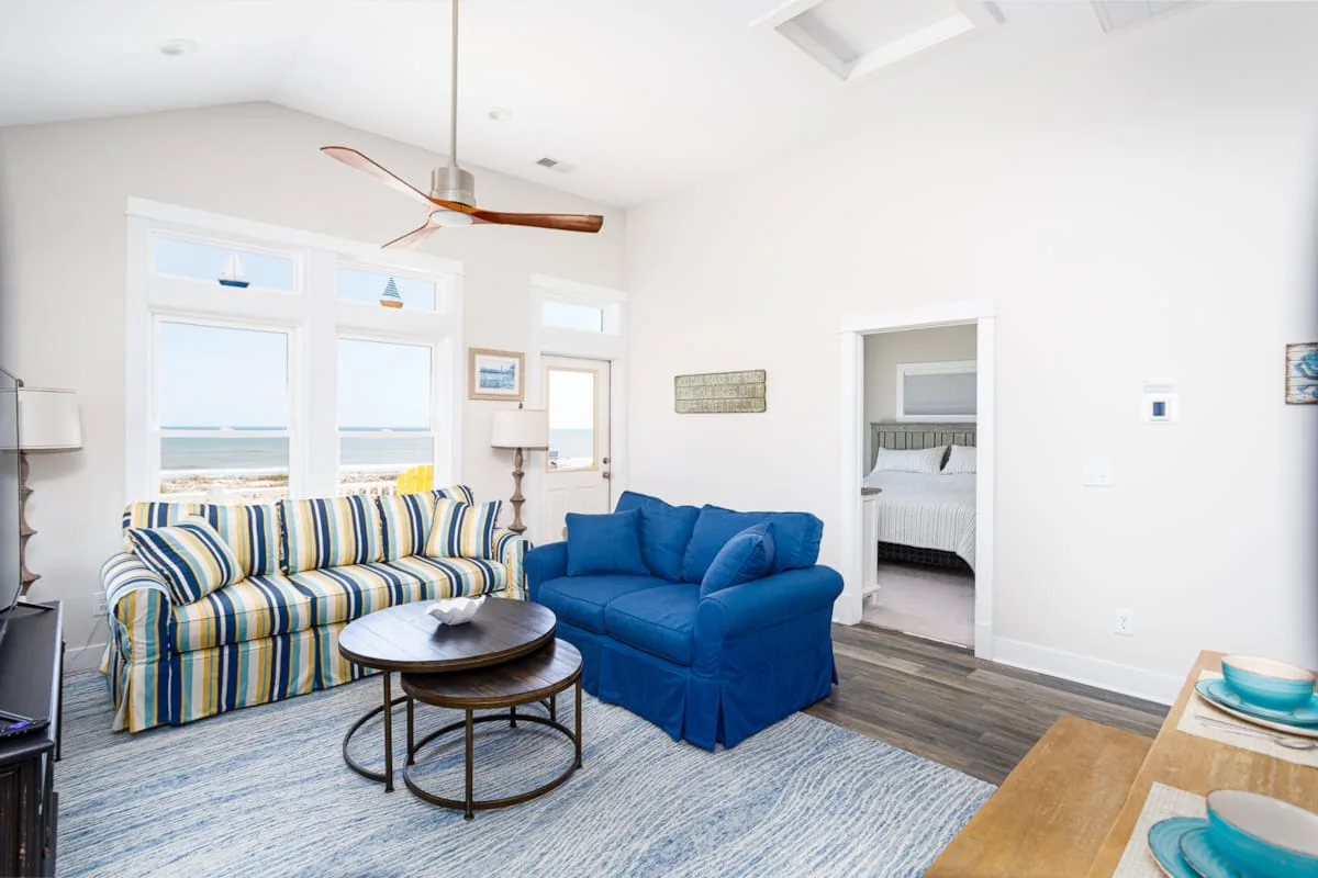 Una sala luminosa con asientos a rayas y un sillón azul junto a las ventanas.