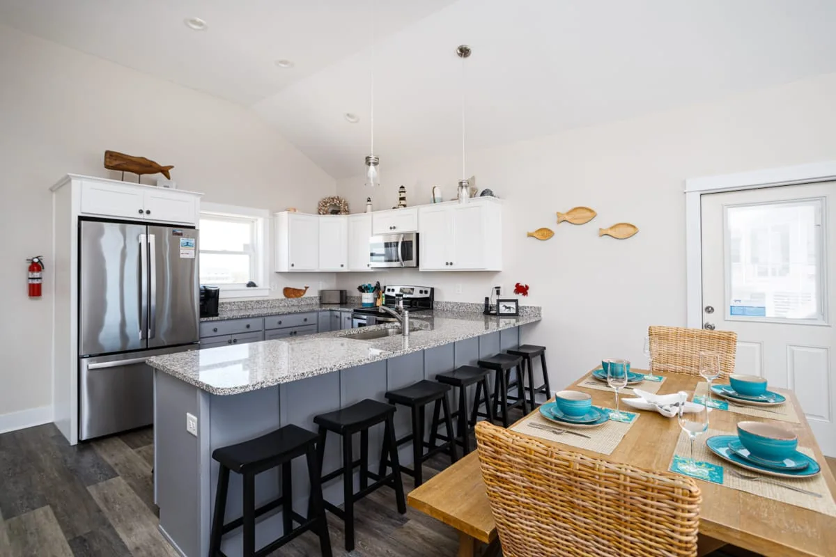 Una cocina luminosa con zona de comedor, una barra central y una mesa preparada.