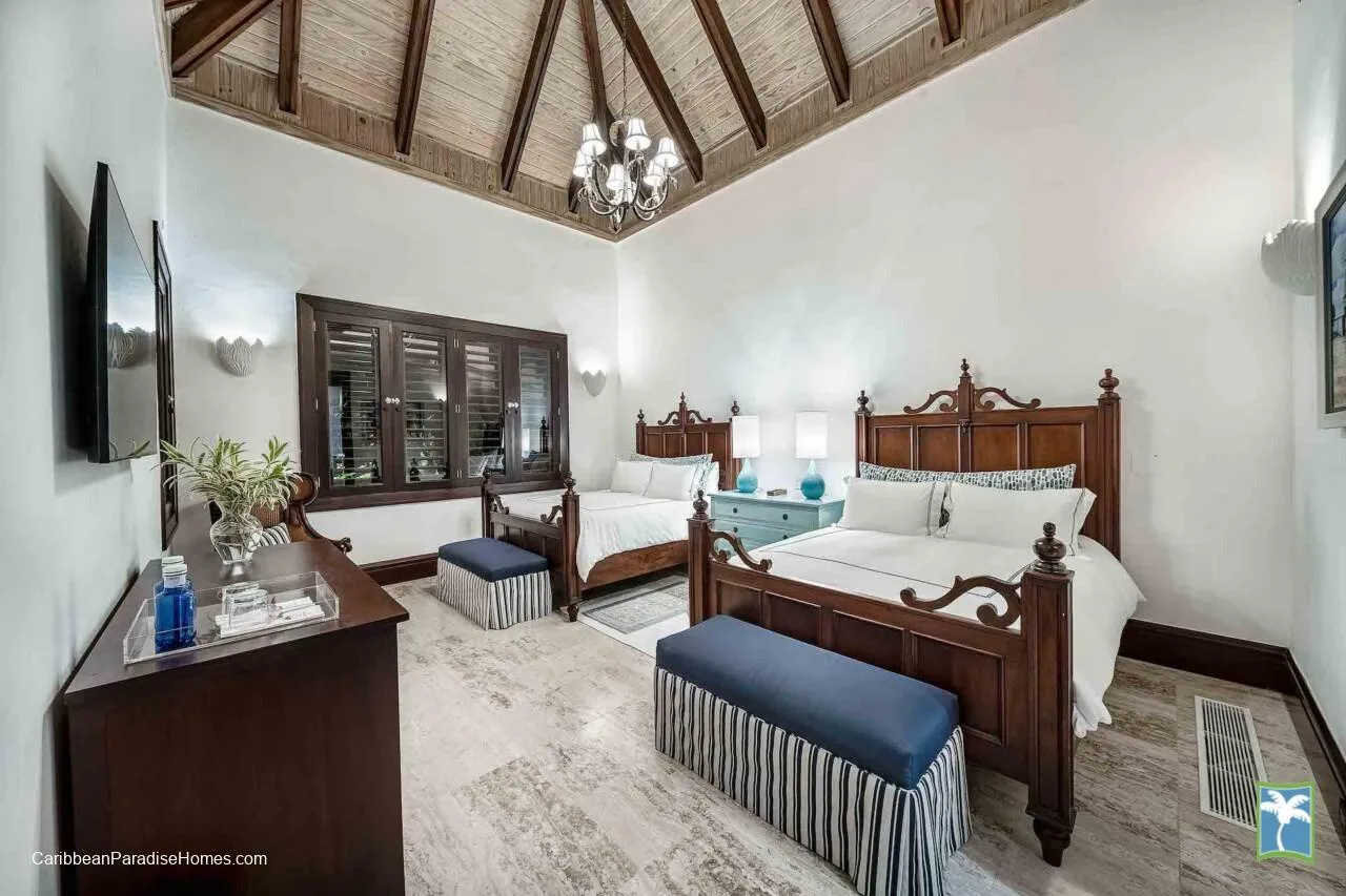 Un dormitorio con dos camas, muebles de madera oscura y un techo alto abovedado.