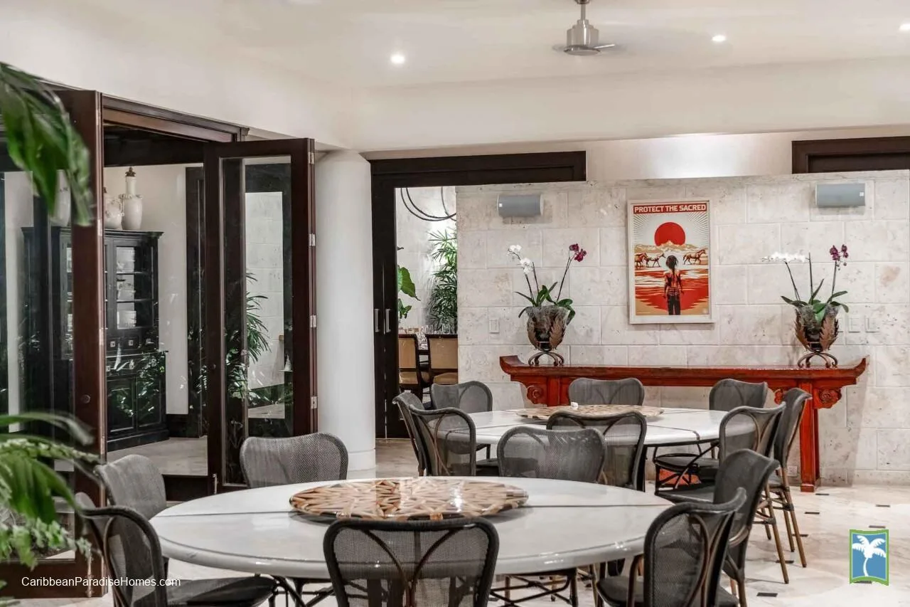 Un comedor con mesas redondas y sillas dispuestas alrededor de una chimenea.