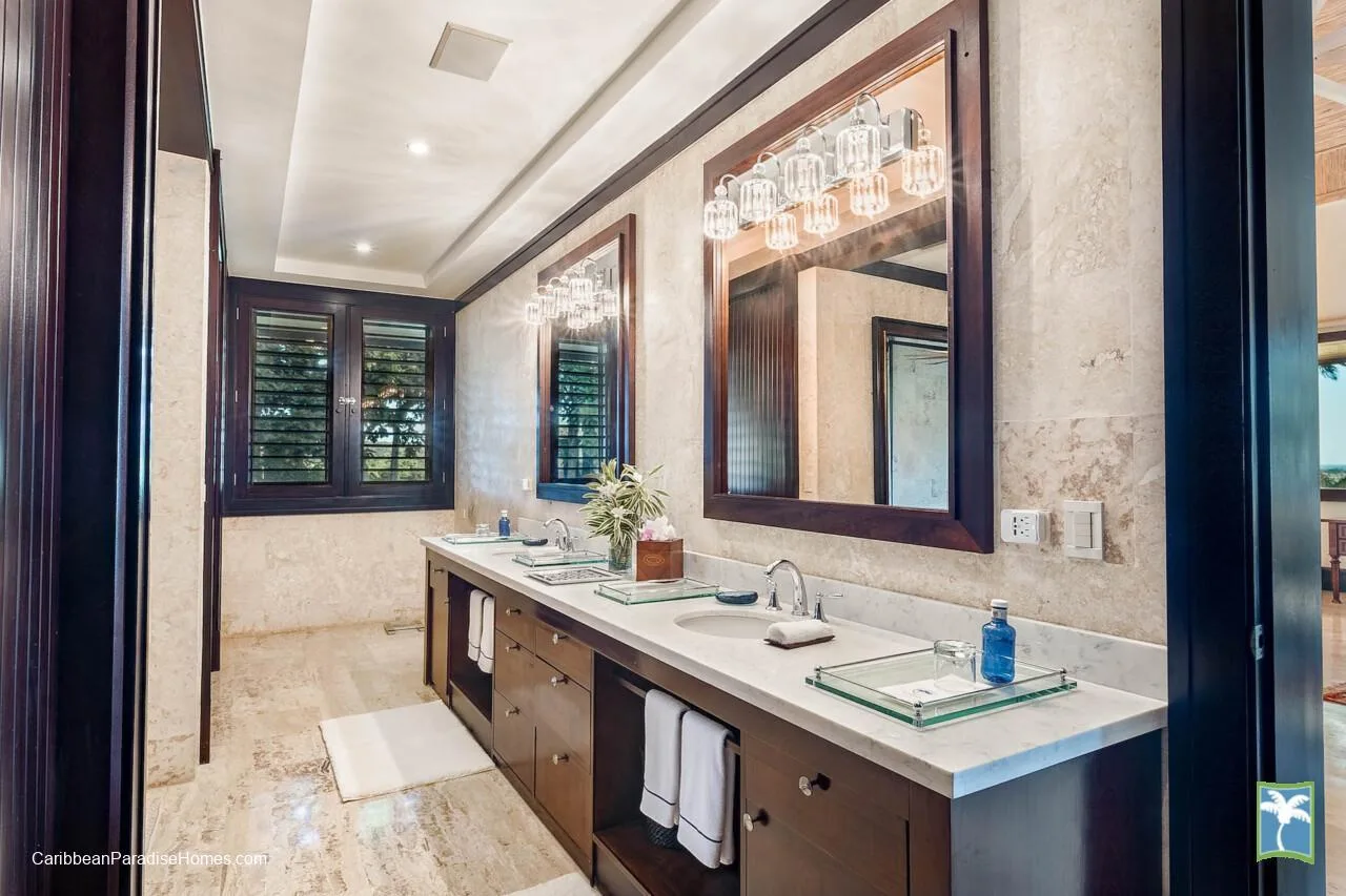 Un baño luminoso con un lavabo largo, dos lavamanos y un espejo grande.