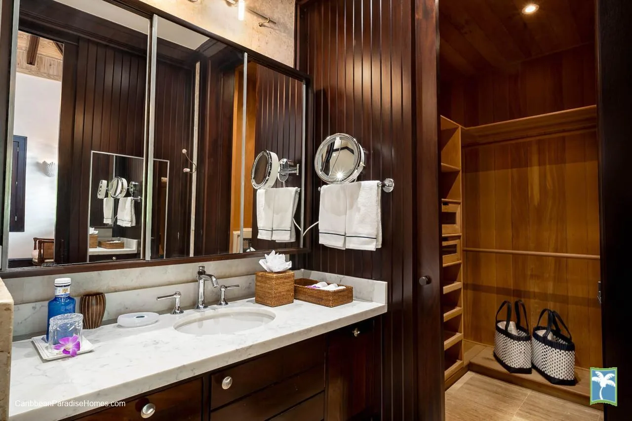 Un tocador de baño con un espejo amplio y un armario de madera abierto.