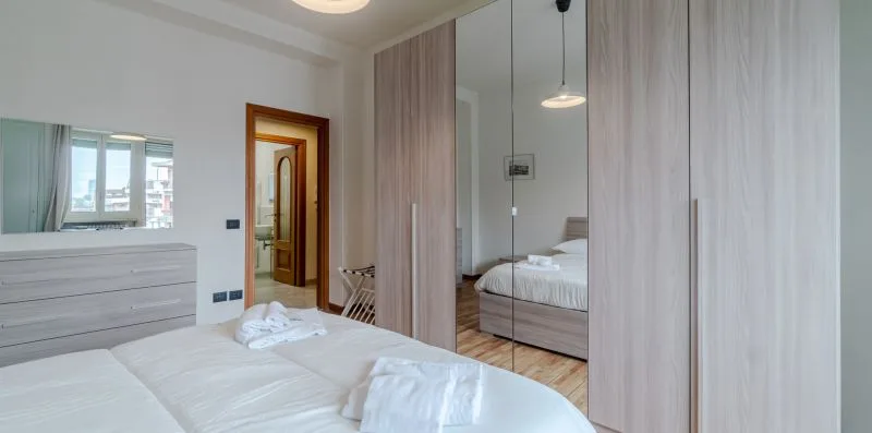Un dormitorio luminoso con cama, armarios con espejo y cómoda.