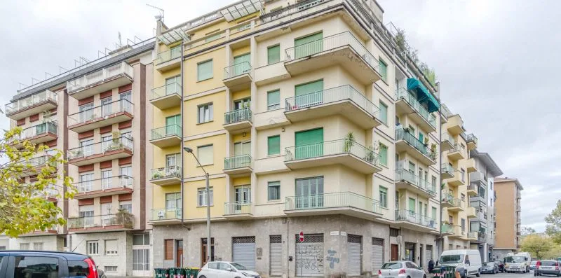 Vista de una calle con un edificio de apartamentos de varias plantas y balcones.
