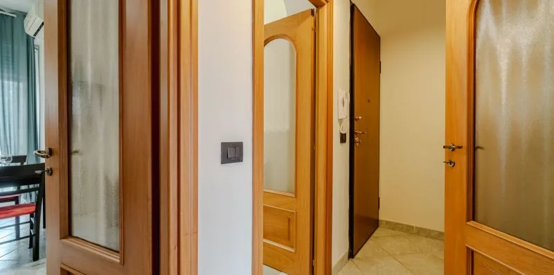 Un pasillo con varias puertas de madera y un panel de puerta con espejo.