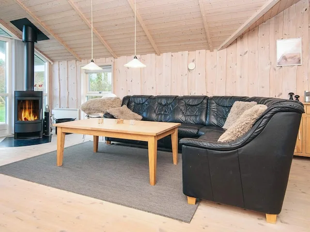 A living room with seating around a wooden coffee table and a lit stove.