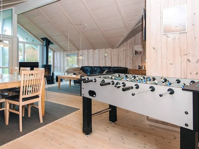 A spacious living and dining area with a foosball table and seating.