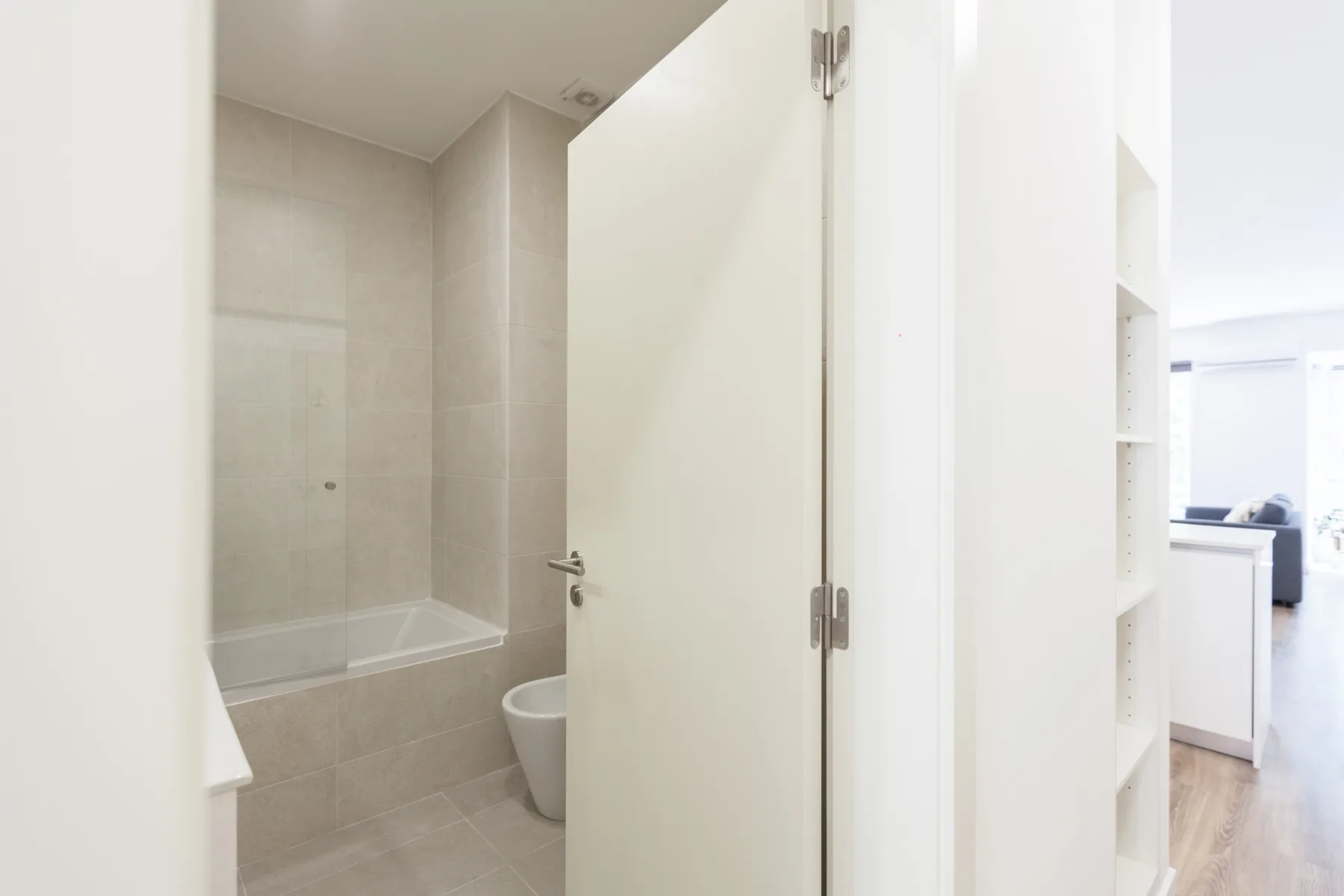 Un baño alicatado con bañera e inodoro se ve a través de la puerta abierta.