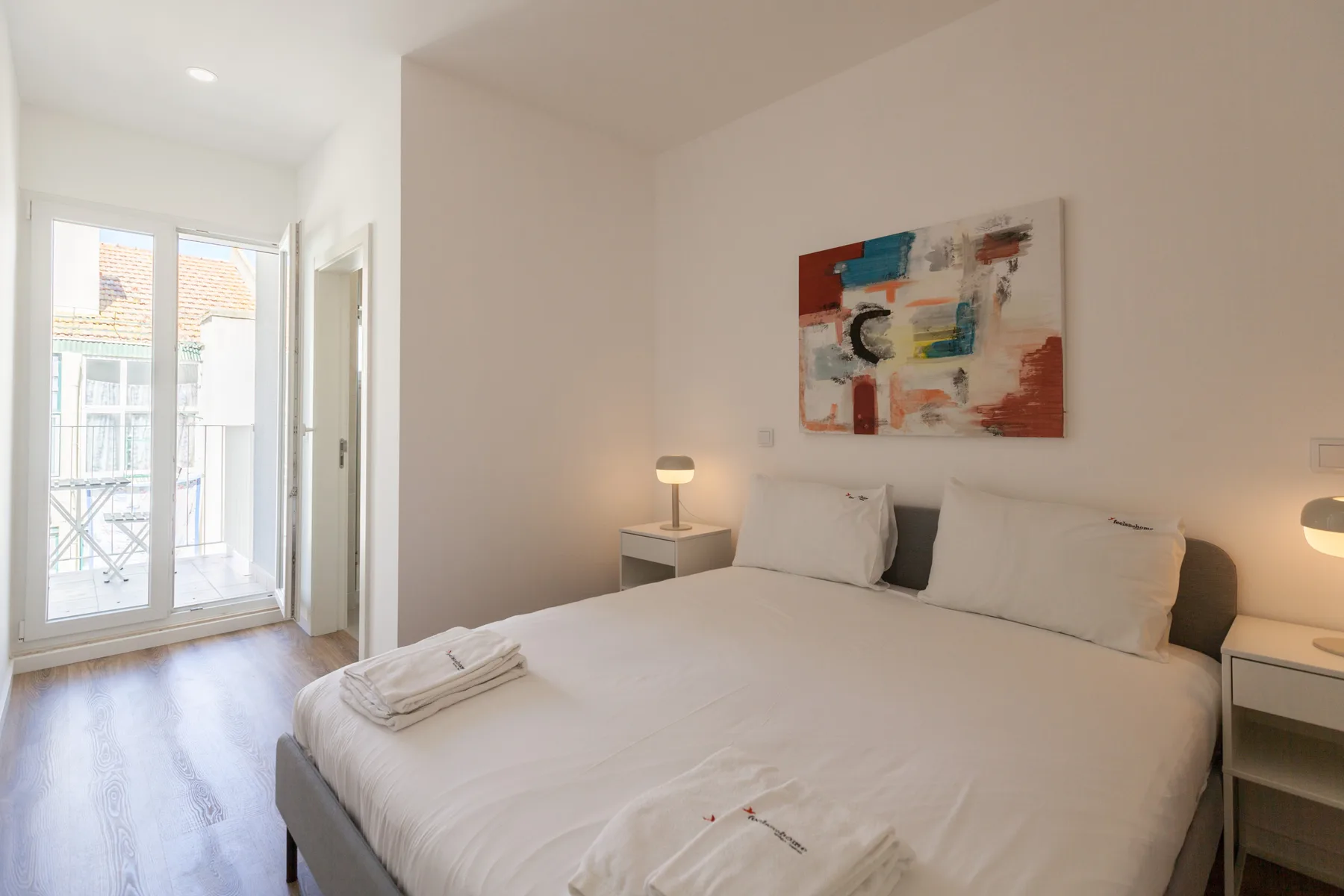 Un dormitorio con una cama bien arreglada y una obra abstracta encima.