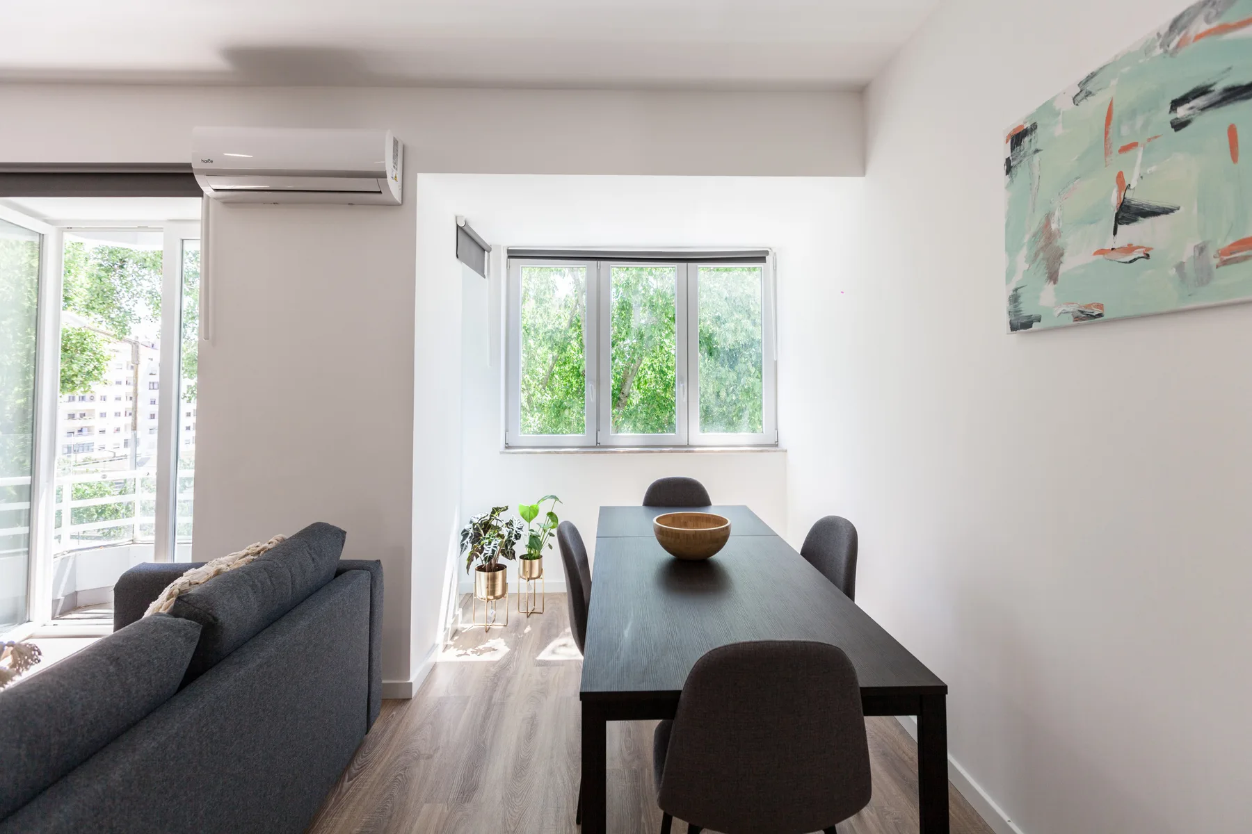 Comedor con una mesa oscura y asientos junto a una ventana luminosa.