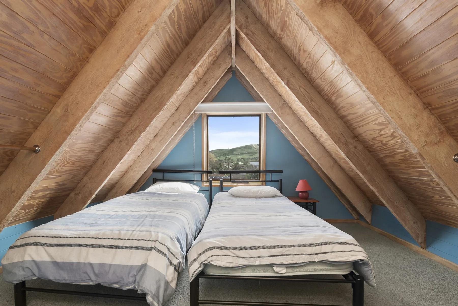 A bedroom with two beds beneath a sloped wooden ceiling.
