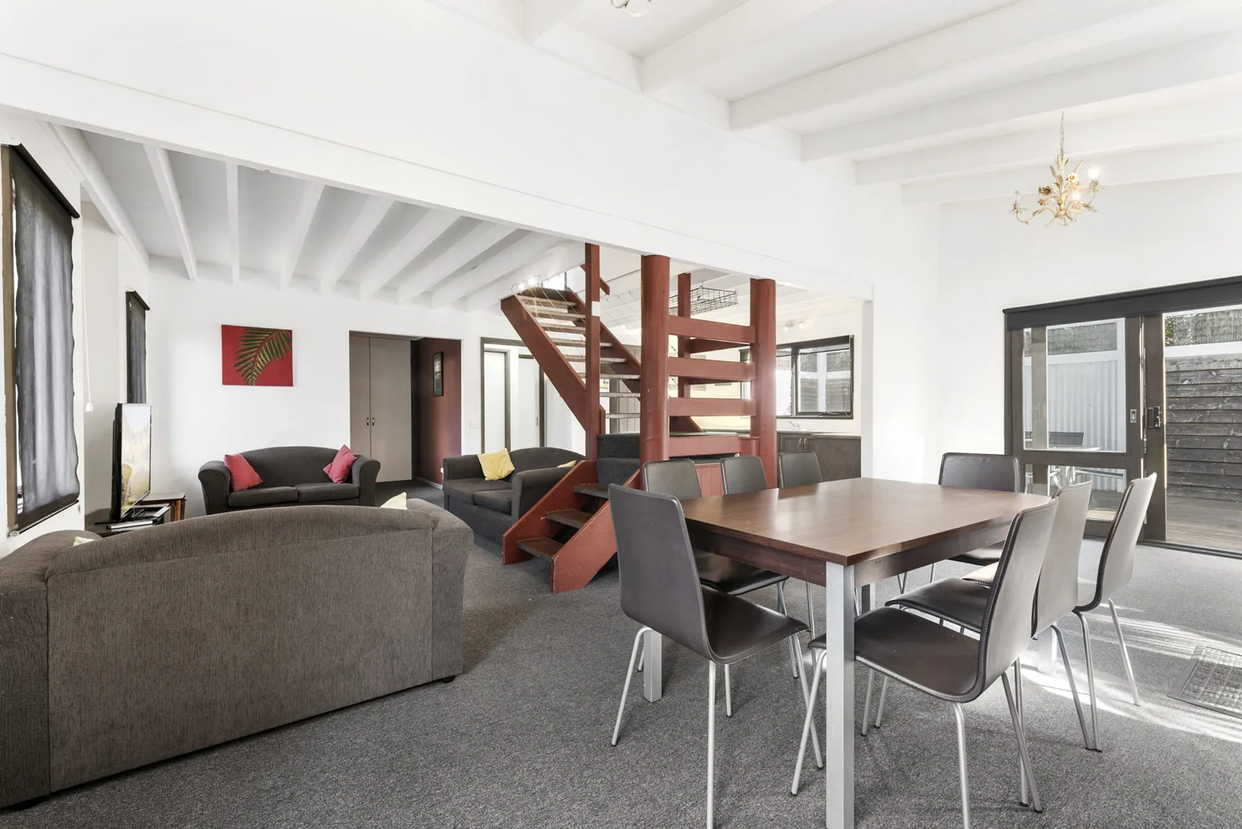 A bright open-plan living and dining area with a wooden staircase.