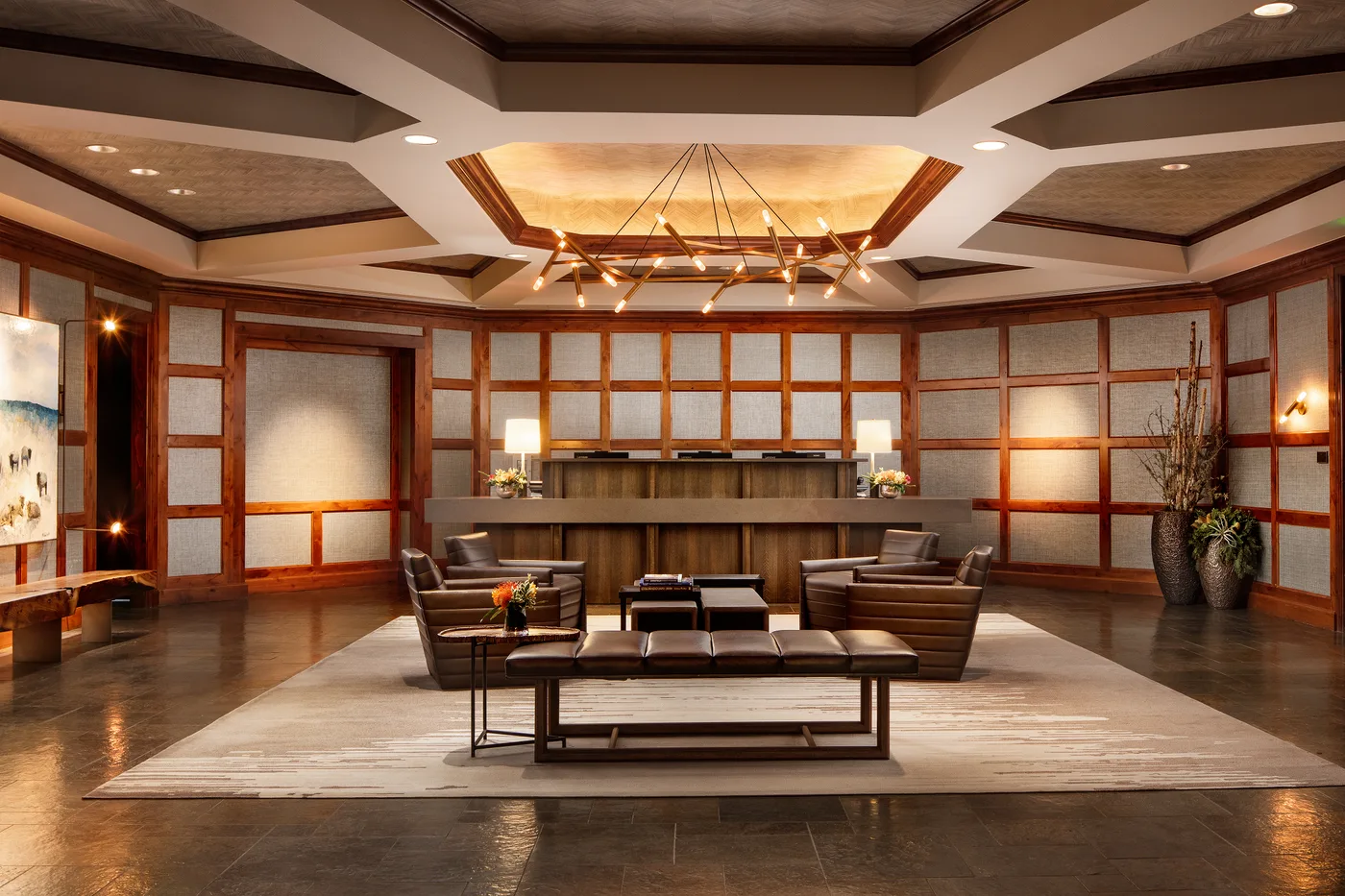 A spacious lounge features seating around a low table beneath a decorative ceiling.