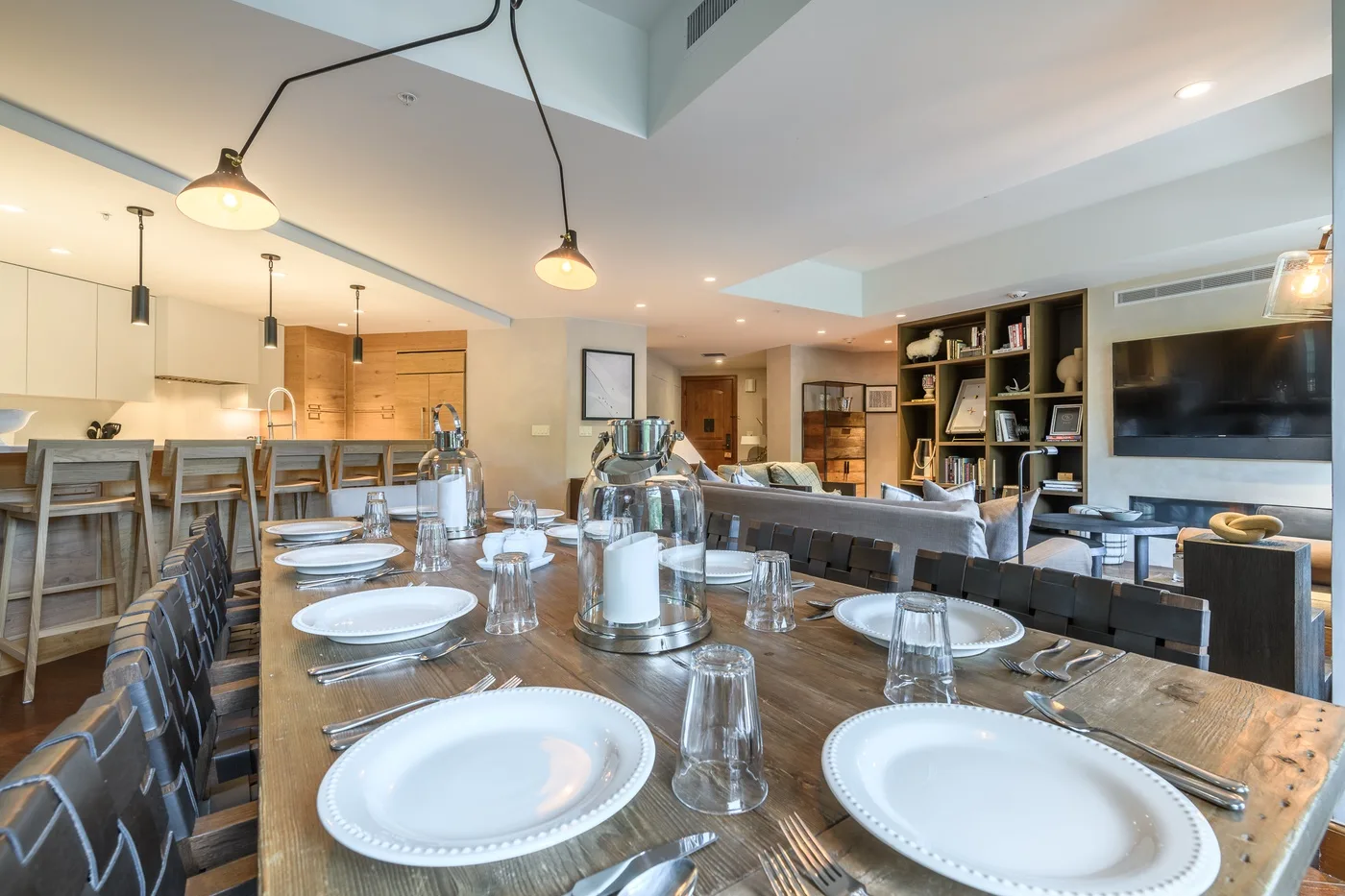 A dining and living area with a long table set with plates and glassware.
