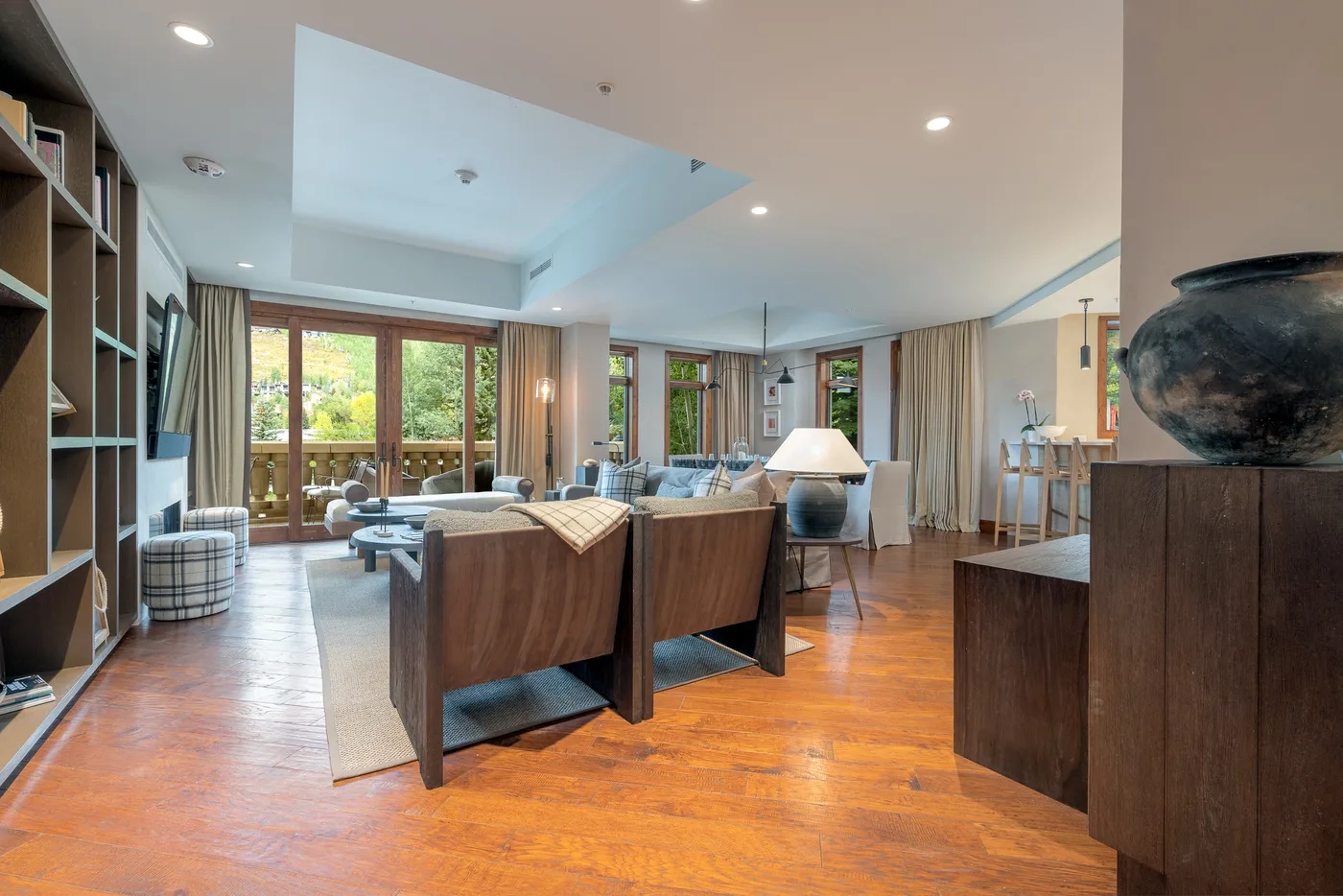 A spacious living room with seating, a rug, and large windows.