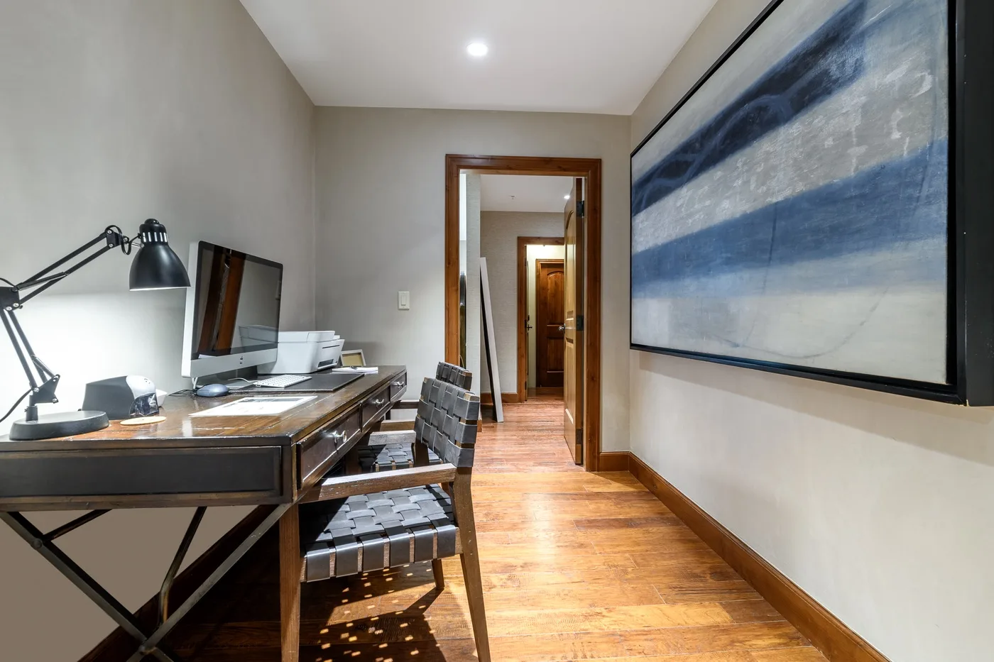 A narrow workspace with a desk and chair beside a hallway.