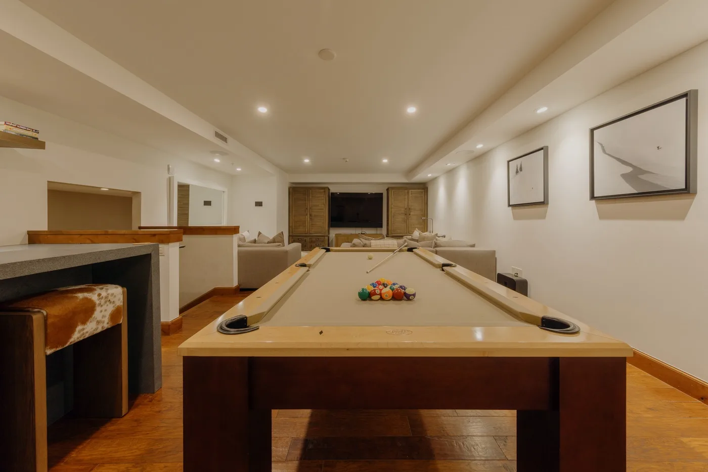 A recreation room with a pool table and framed artwork on the walls.