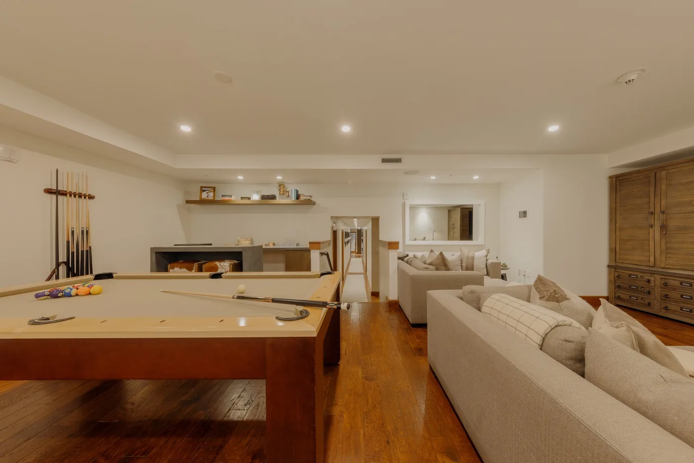 A recreation room with a pool table and lounge seating.