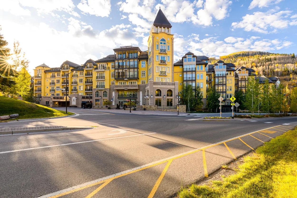 A large yellow building with a central tower stands beside a paved road.