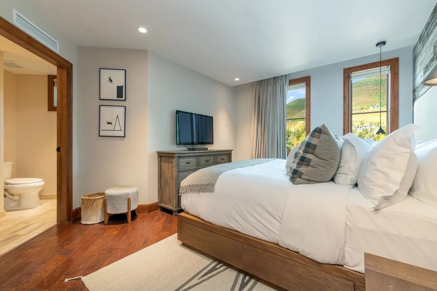A bedroom with a neatly made bed and a television on a dresser.