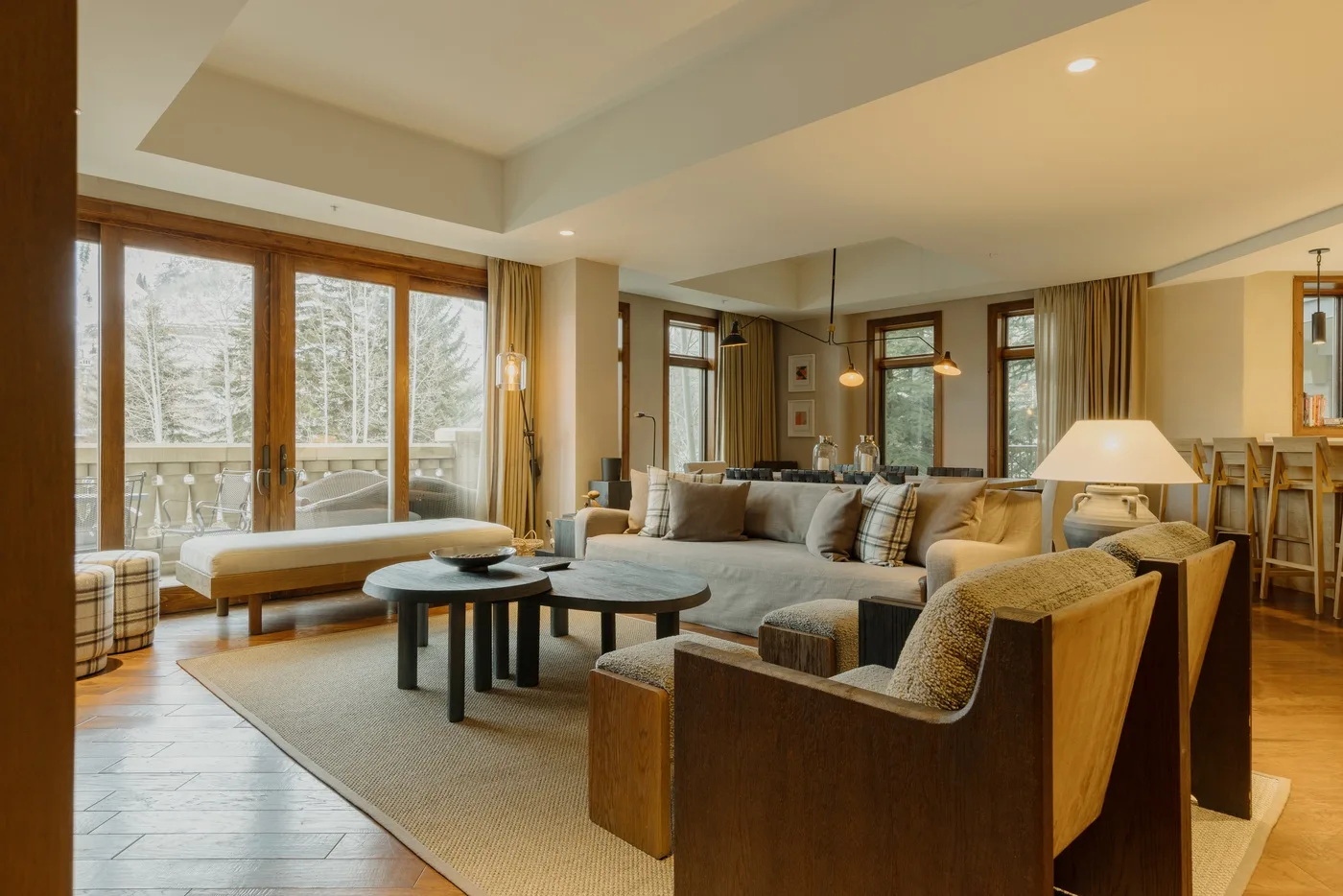 A living room with a seating area and large windows overlooking trees.