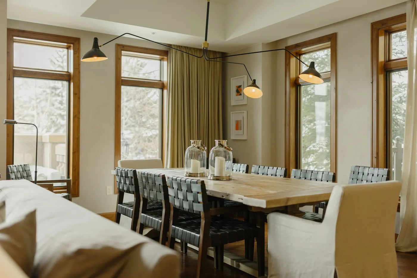 A dining room with a long table, chairs, and tall windows.
