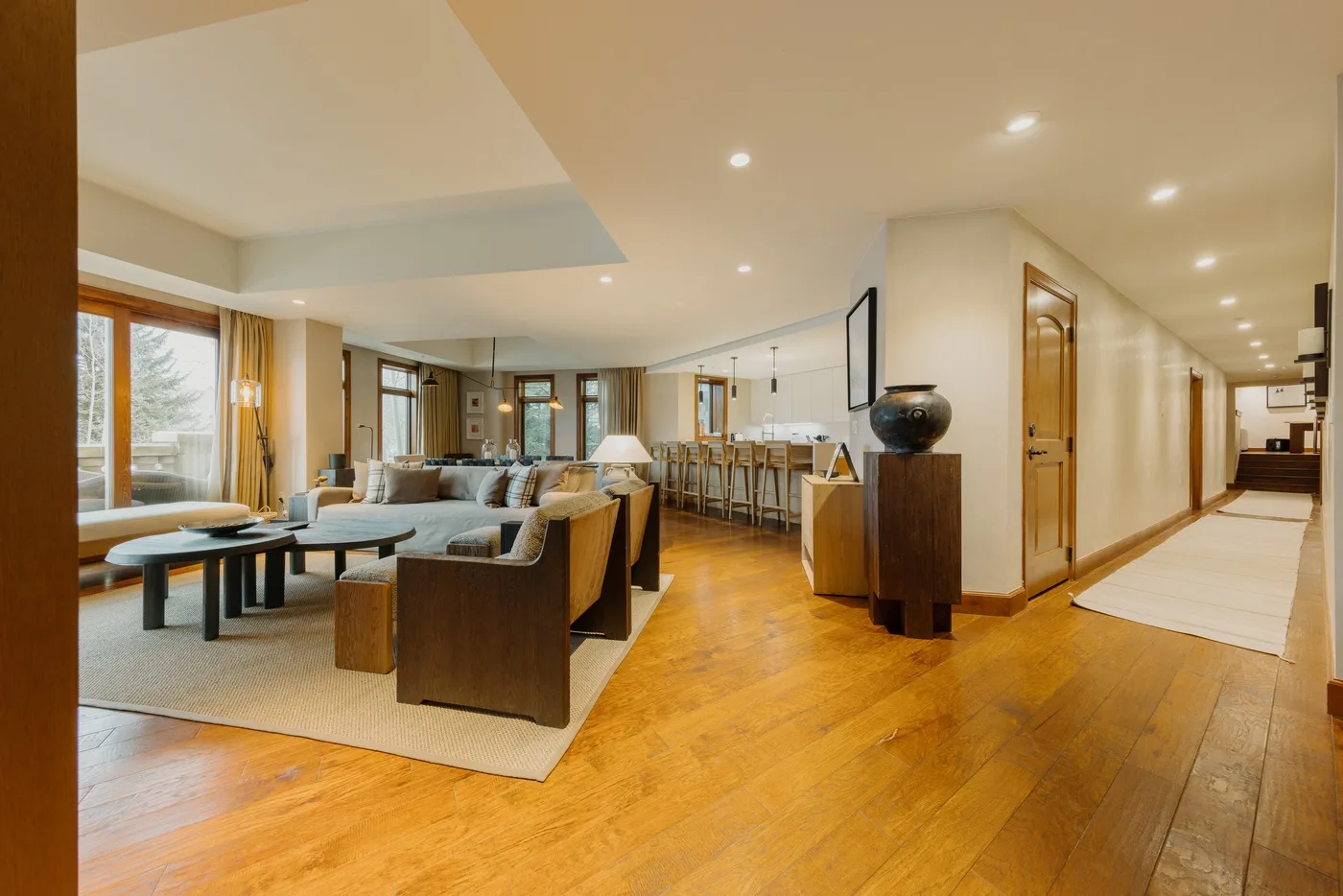 An open-plan living and dining area with seating, tables, and a hallway.