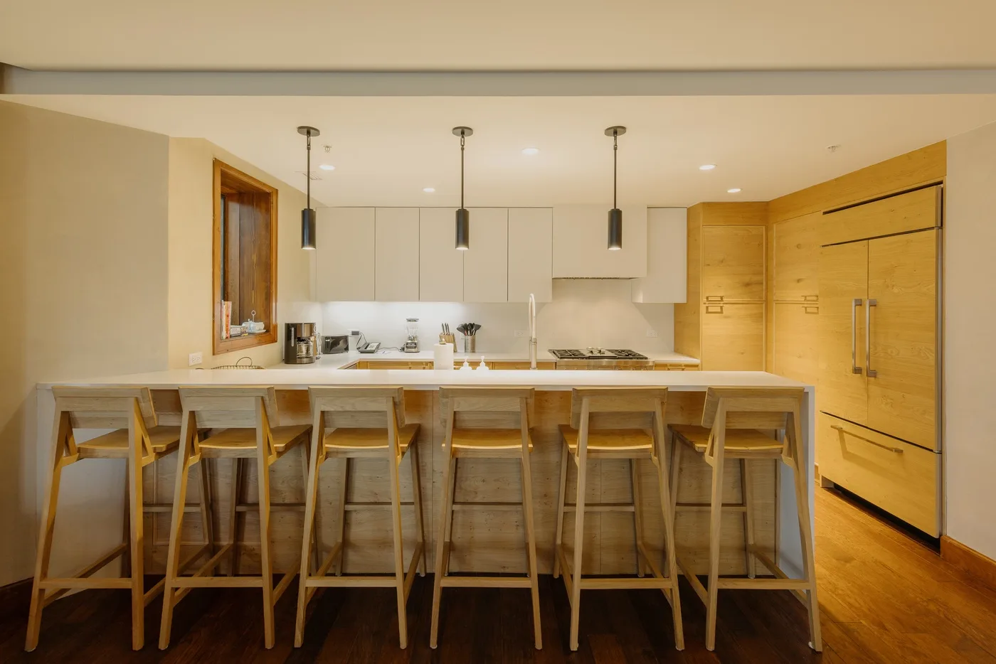 A modern kitchen with a long island and wooden bar stools.
