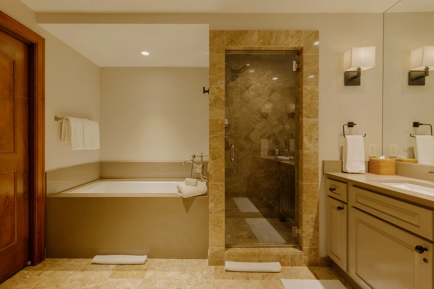 A bathroom with a bathtub, glass shower, and vanity.