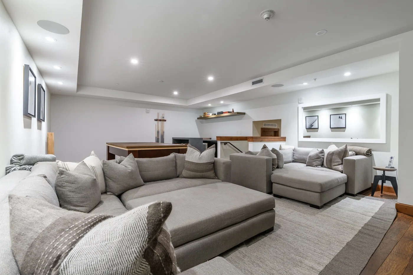 A spacious lounge with gray seating arranged around a low central table.