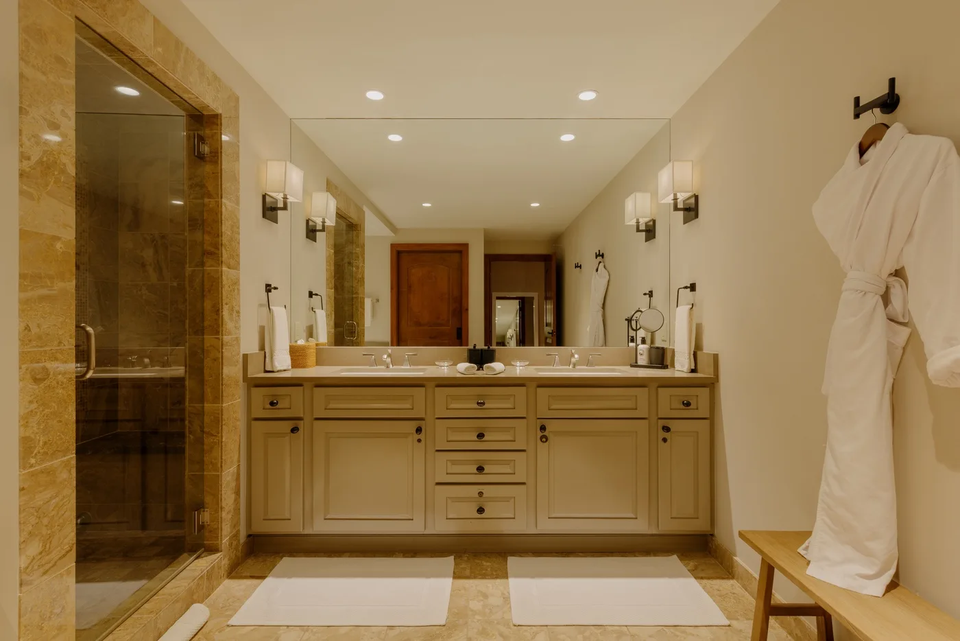 A spacious bathroom with a long vanity, mirrors, and a glass shower.