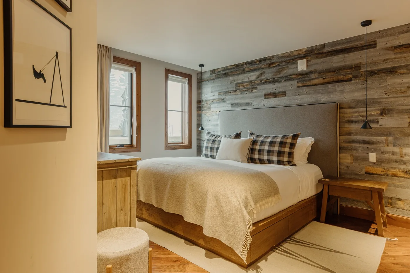 A bedroom with a neatly made bed and wood-paneled accent wall.