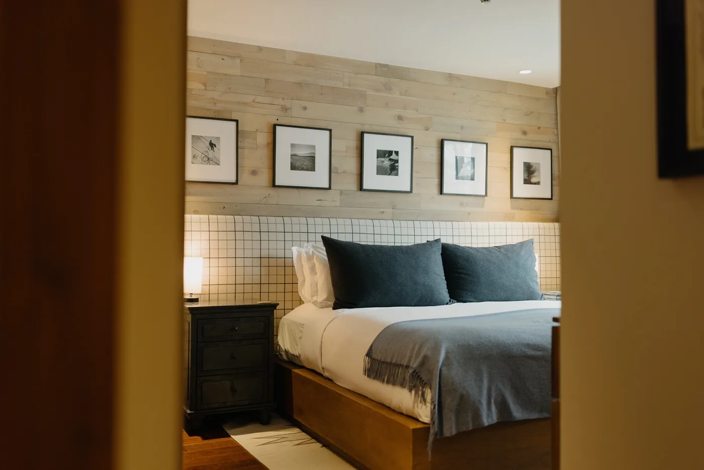 A bedroom with a bed dressed in white linens and dark pillows.