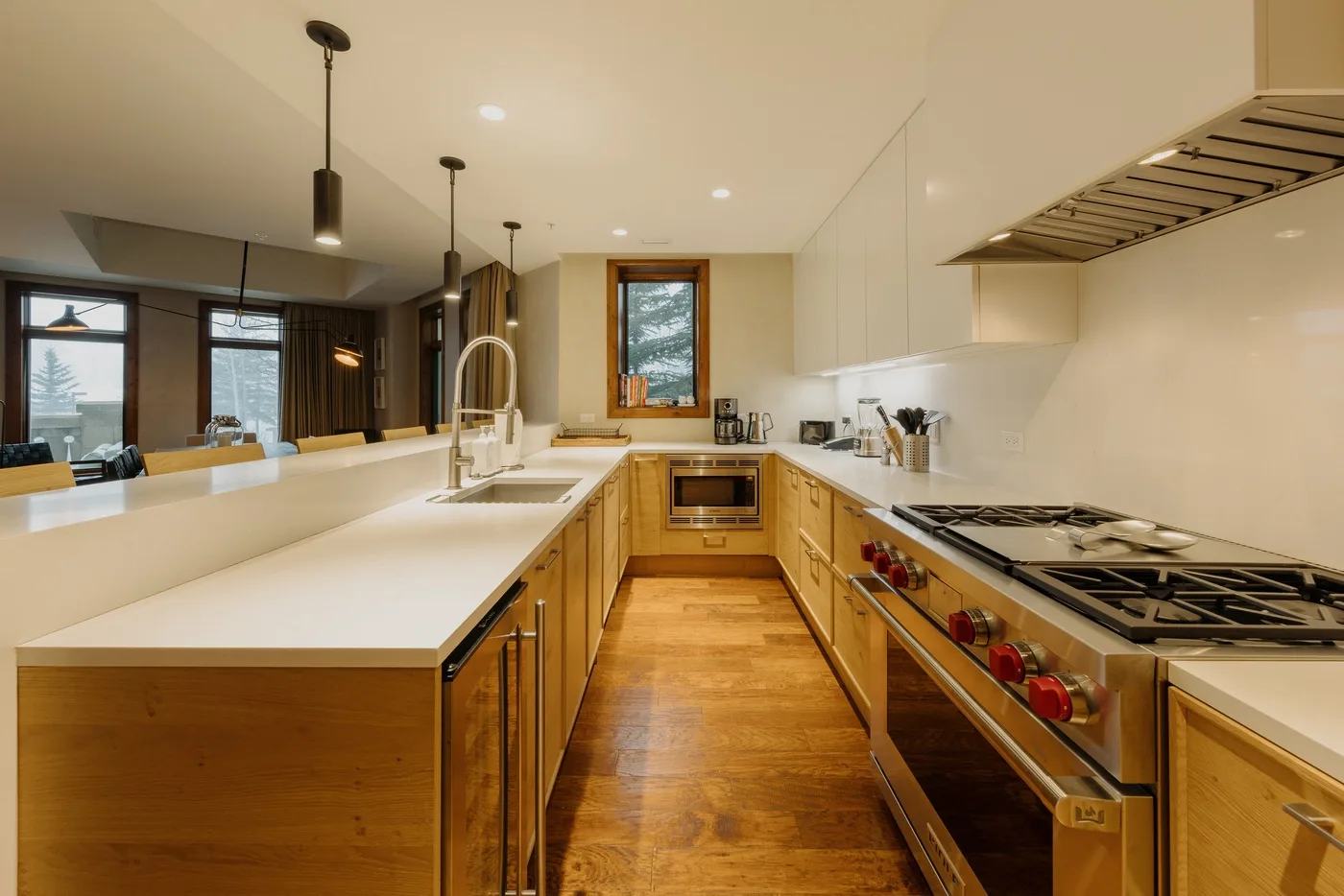 A bright kitchen with a long island, wooden cabinetry, and a large range.