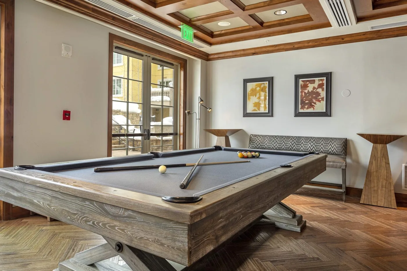 A recreation room with a pool table and seating along the wall.