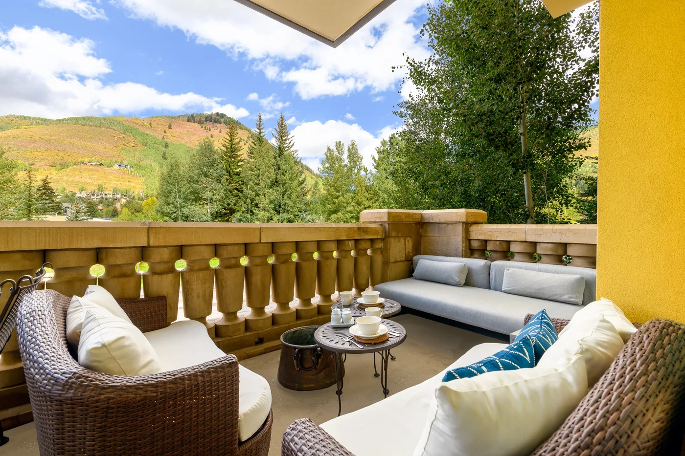 An outdoor balcony seating area overlooks green trees and rolling hills.
