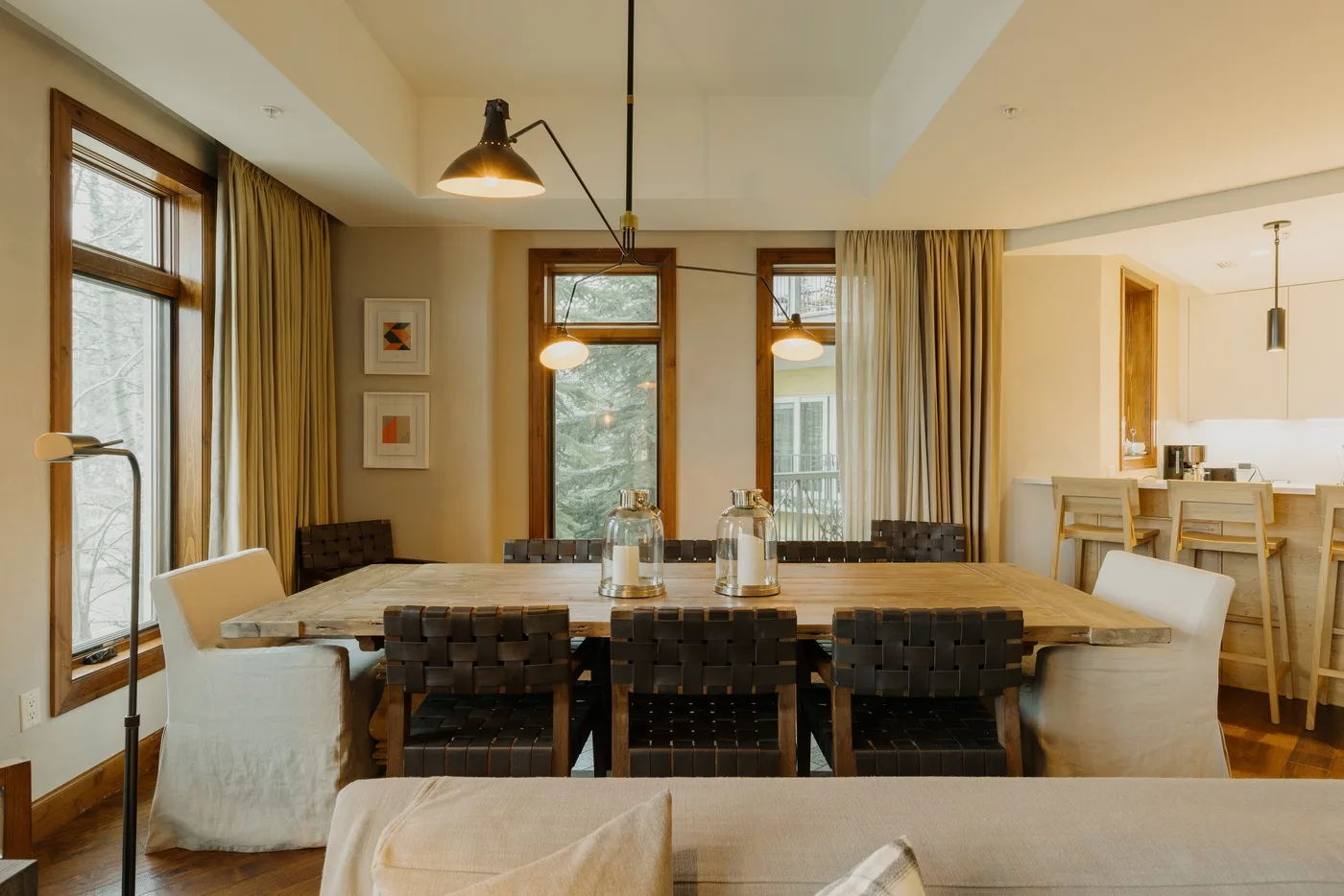 A dining area with a long table and chairs beneath pendant lights.